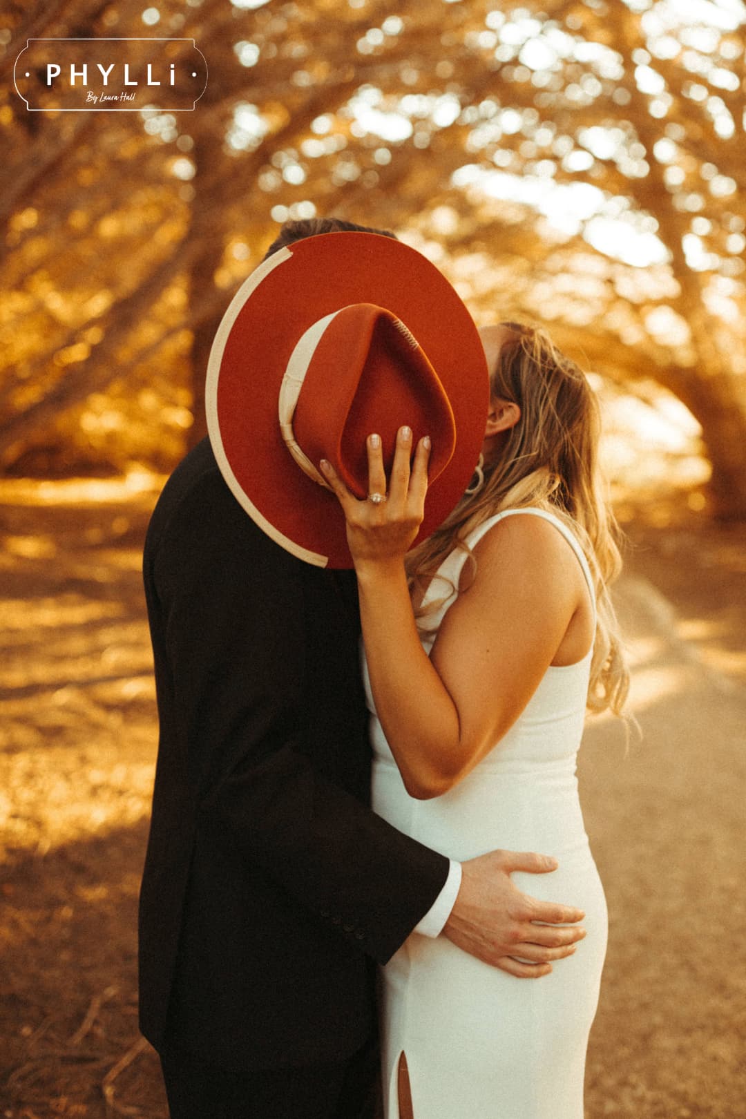 Couple embracing with the spiced pumpkin Producer felt hat between them in warm evening light.