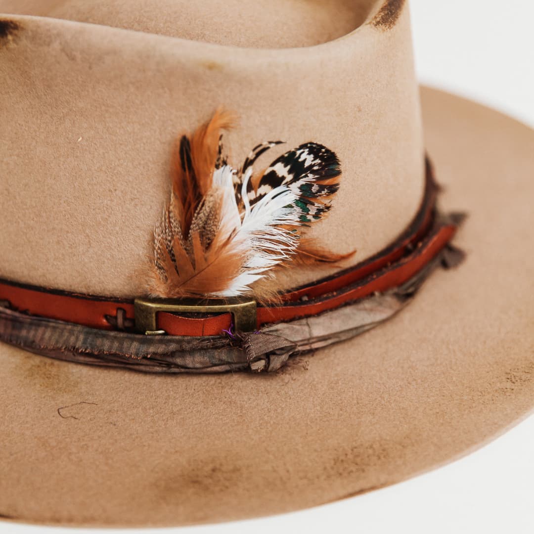 Close up of feather bunch and antique leather belt band on The Safari felt hat by PHYLLi Designs.