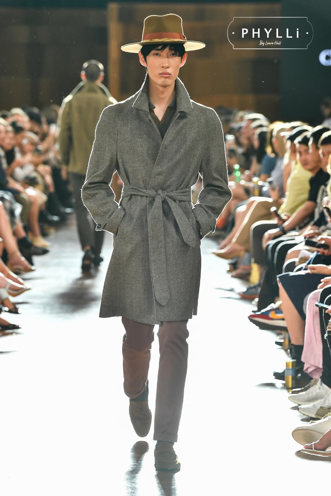 Model walking runway wearing caramel felt hat by PHYLLi Designs styled with a tailored coat.