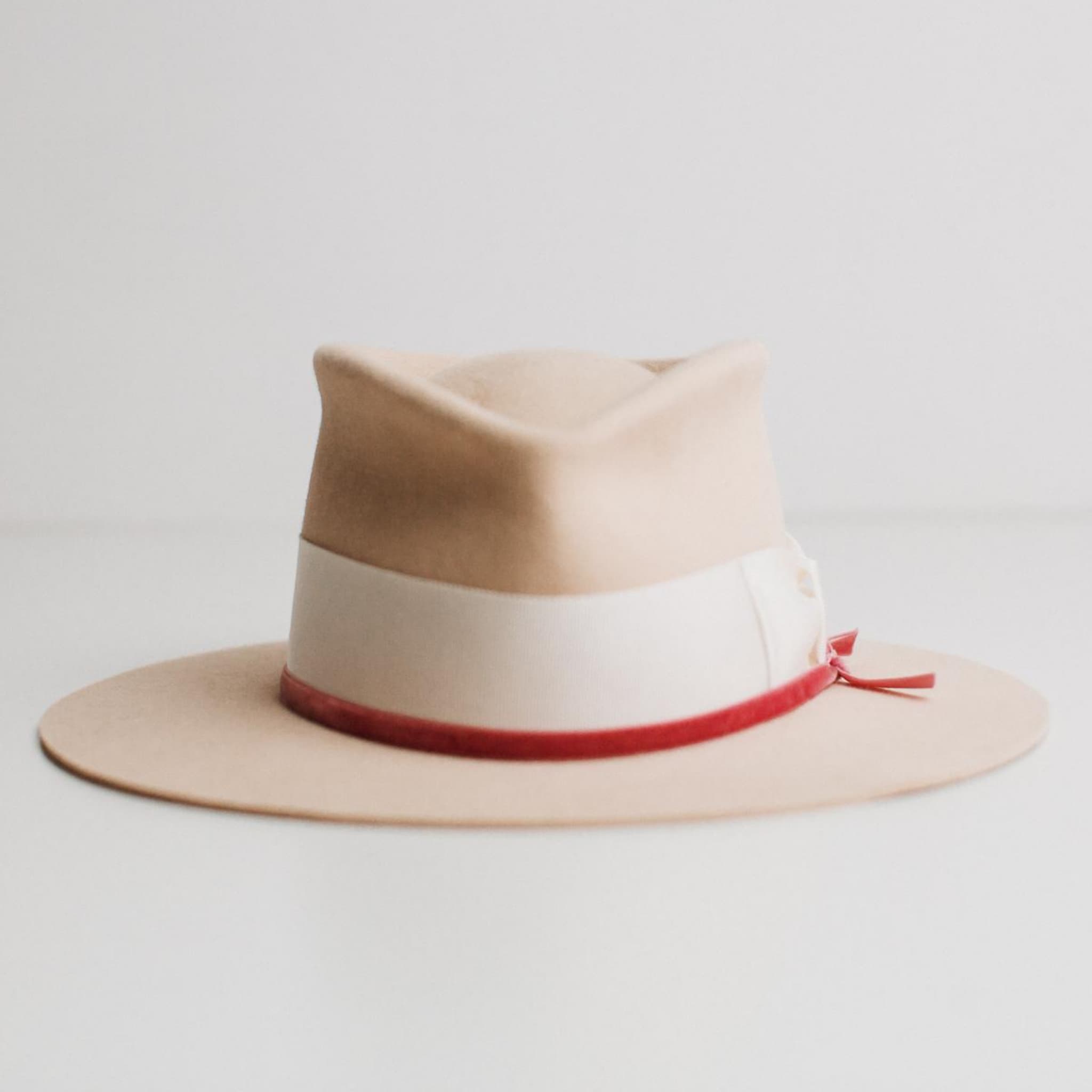 Front view of beige felt hat with ivory band and pink velvet ribbon by PHYLLi Designs on a light grey background.