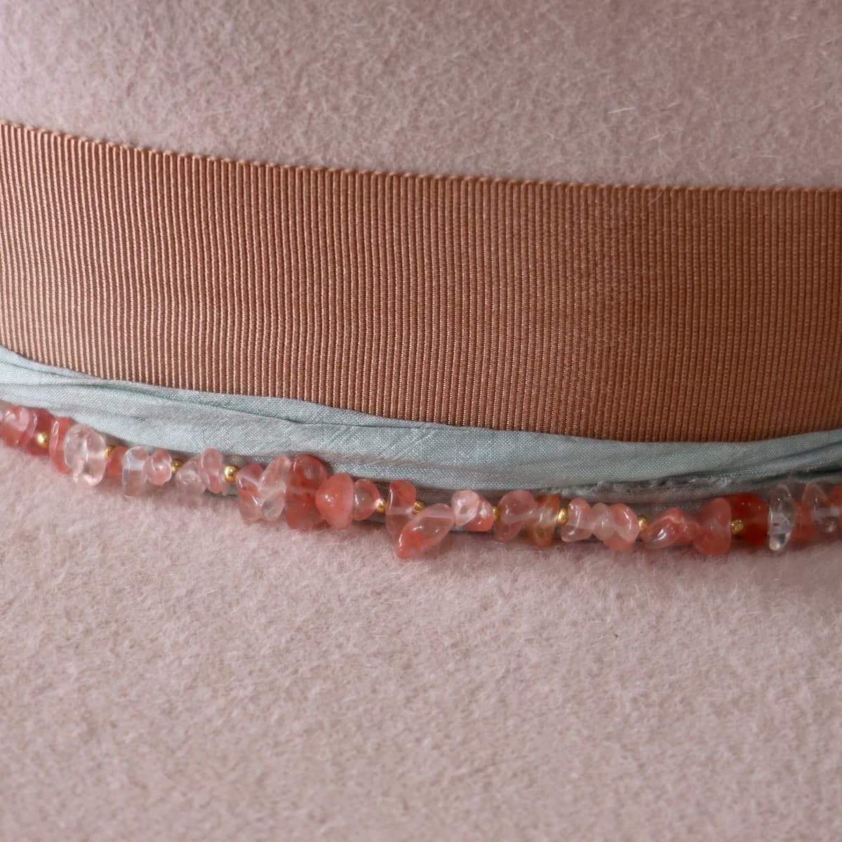 Close up detail of the Tourmaline felt hat showing rose quartz hat necklace set against the baby pink rabbit felt.