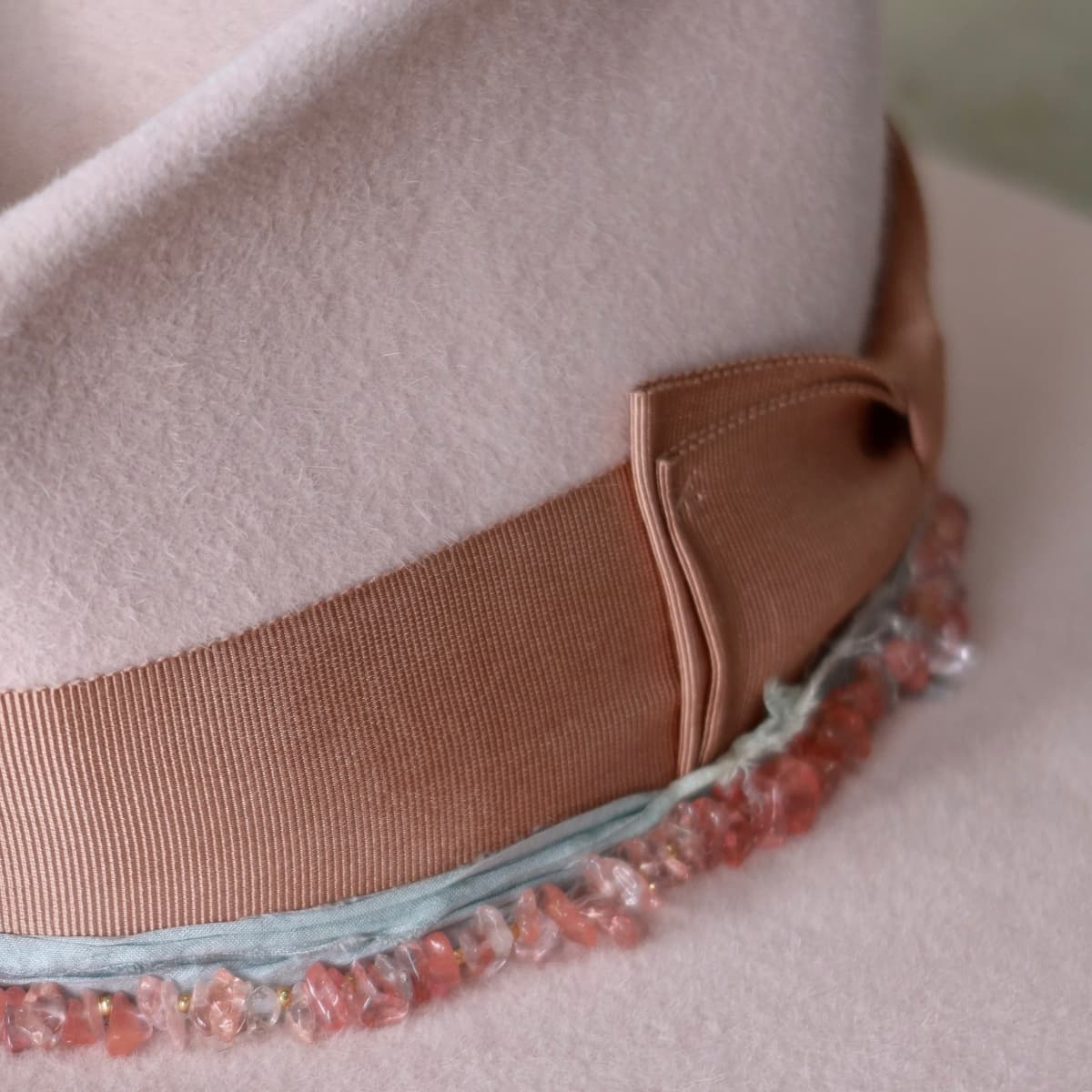 Close up detail of the Tourmaline felt hat showing rose quartz stone hat necklace and gold spacer beads.