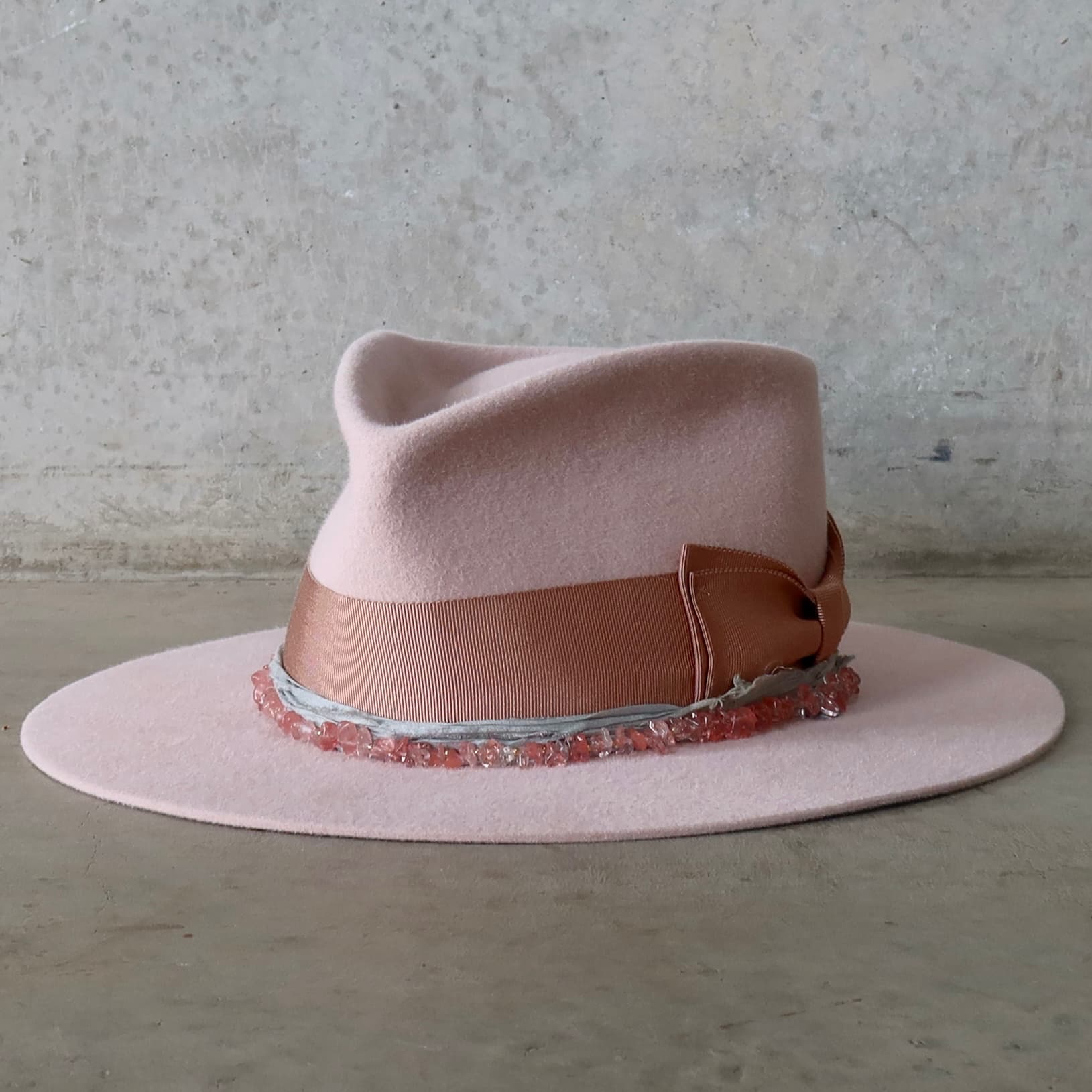 Front left angle of the Tourmaline Baby Pink felt hat by PHYLLi Designs with dirty rose grosgrain double bow and rose quartz hat necklace.