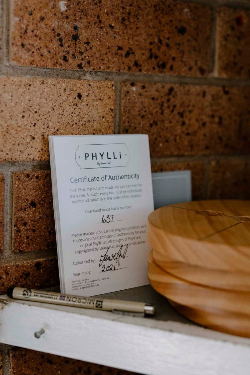 PHYLLi certificate of authenticity displayed beside wooden hat block in the studio.