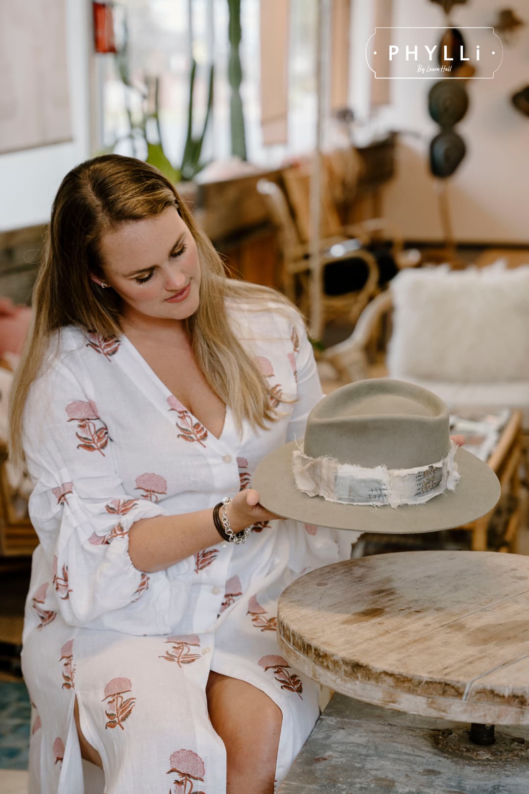 Laura Hall, founder of PHYLLi Designs, holding the Wabi Limited Edition Sahara felt hat with Wabi Sabi patch band in a warm studio setting.