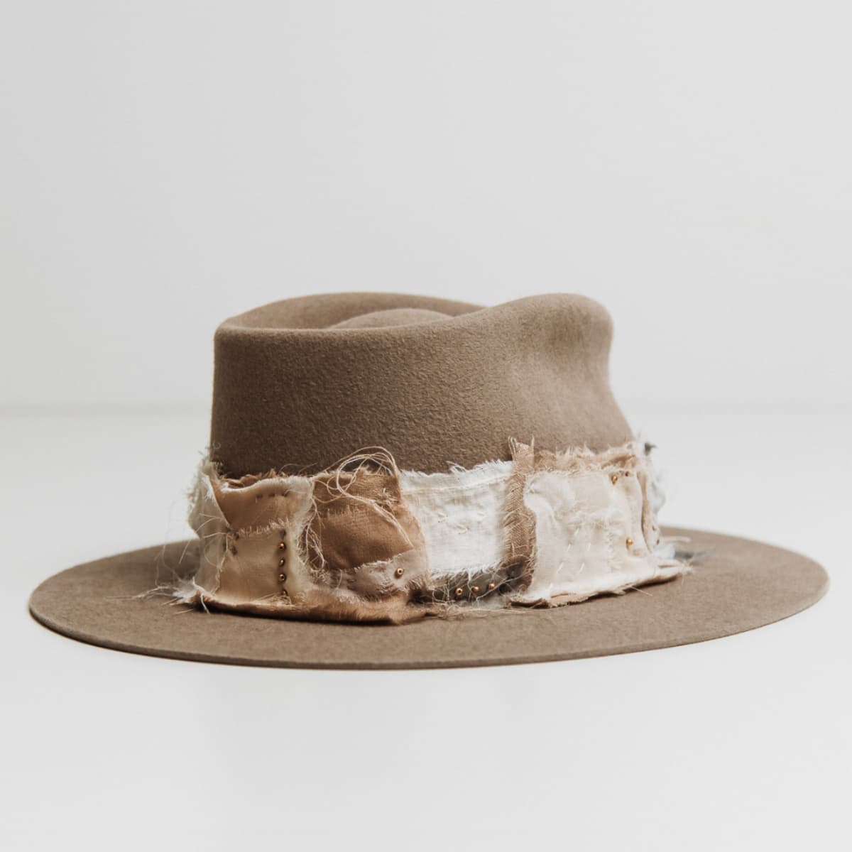 Back right angle of the Wabi Limited Edition Sahara felt hat by PHYLLi Designs featuring Wabi Sabi patch band with sashiko stitching and matte gold bead accents.