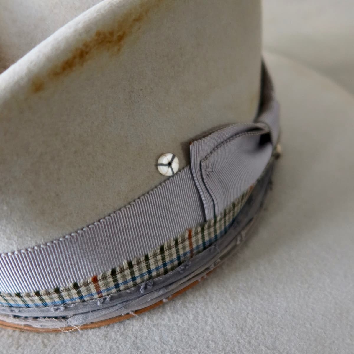 Close up detail of the Watson Limited Edition felt hat showing Japanese grosgrain bow band with textured grey sari silk trim and grandpa check cotton trimming.
