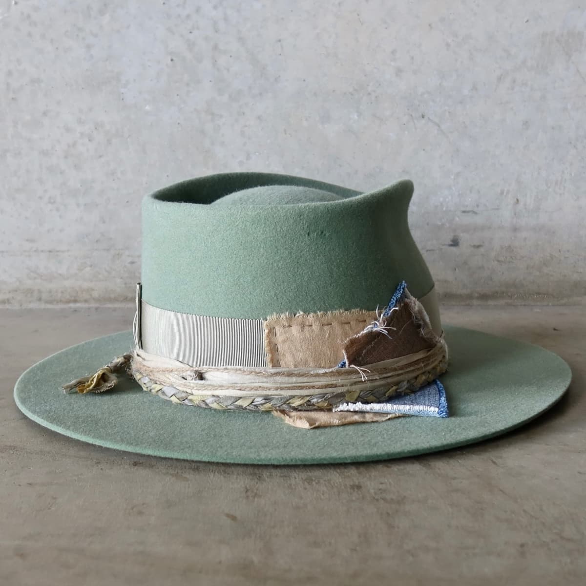 Back right angle of the Eucalyptus felt hat Wheatley Limited Edition by PHYLLi Designs featuring wabi sabi linen and denim patches with plaited sari silk trim.