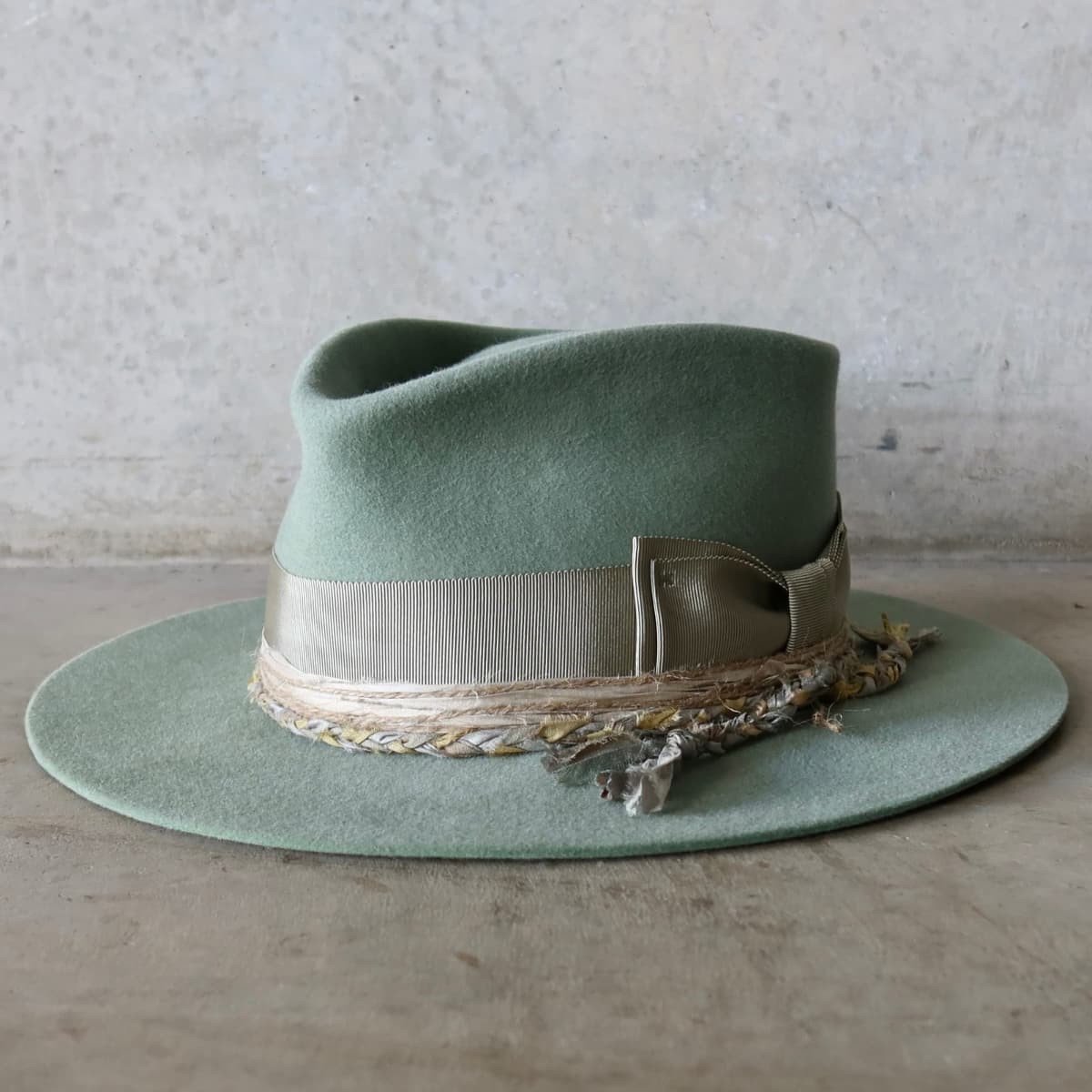 Front left angle of the Eucalyptus felt hat Wheatley Limited Edition by PHYLLi Designs with Japanese grosgrain bow band, plaited sari silk trim and twine wraps.