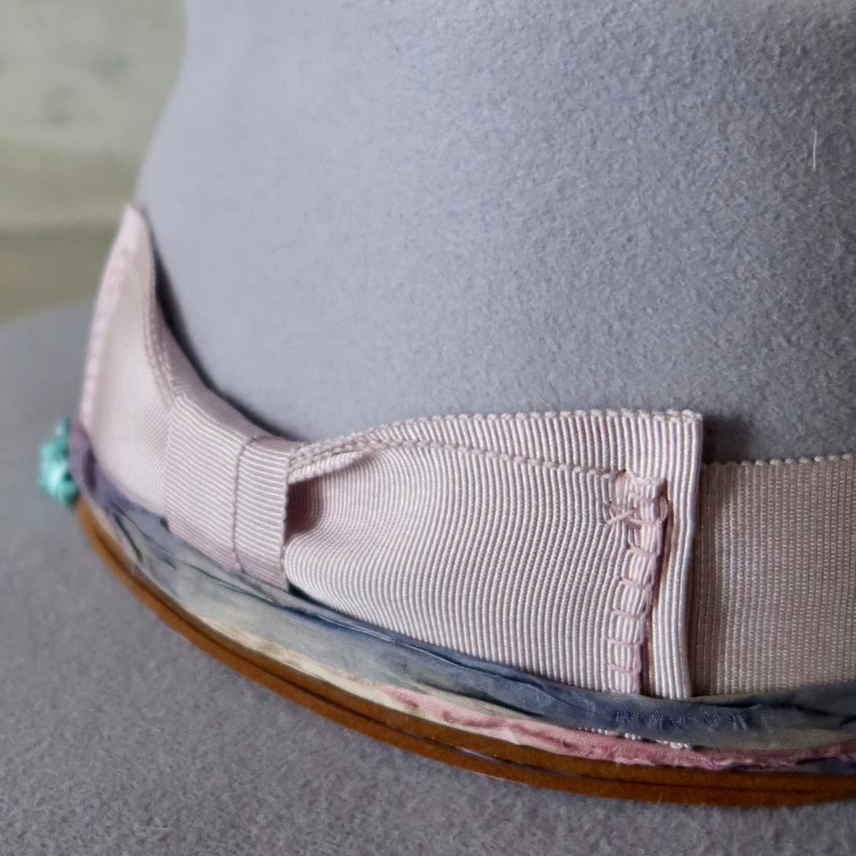 Close up detail of the Wolseley felt hat showing turquoise crystal cluster with sari silk trimming in blue and pink.