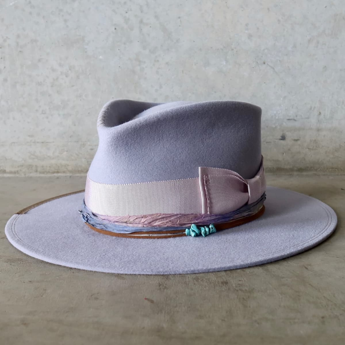 Front left angle of the Lilac felt hat Wolseley by PHYLLi Designs with turquoise crystal cluster and tie dye sari silk trim.