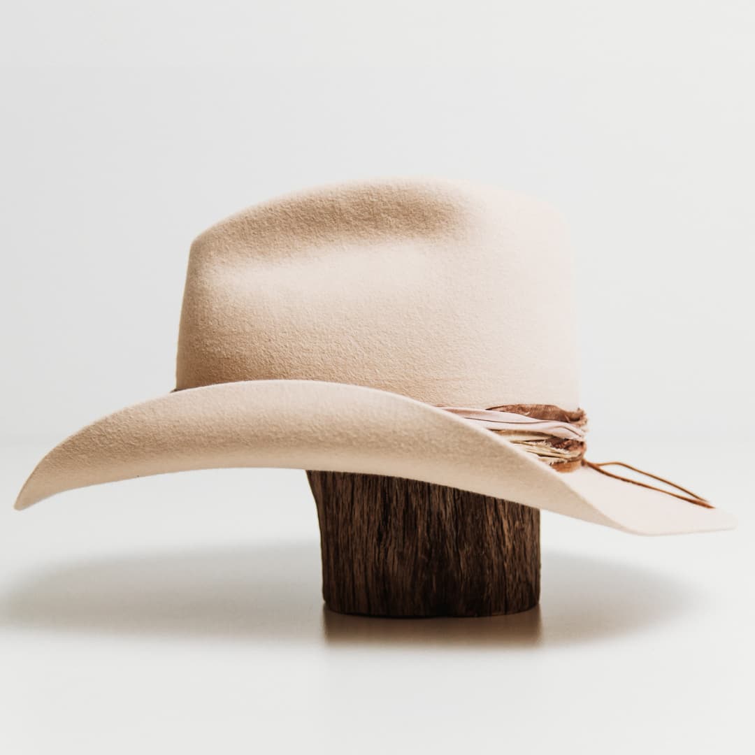 Left side view of the Wrapped Wheeler beige felt hat by PHYLLi Designs with sari silk wrapped band and tan suede string.