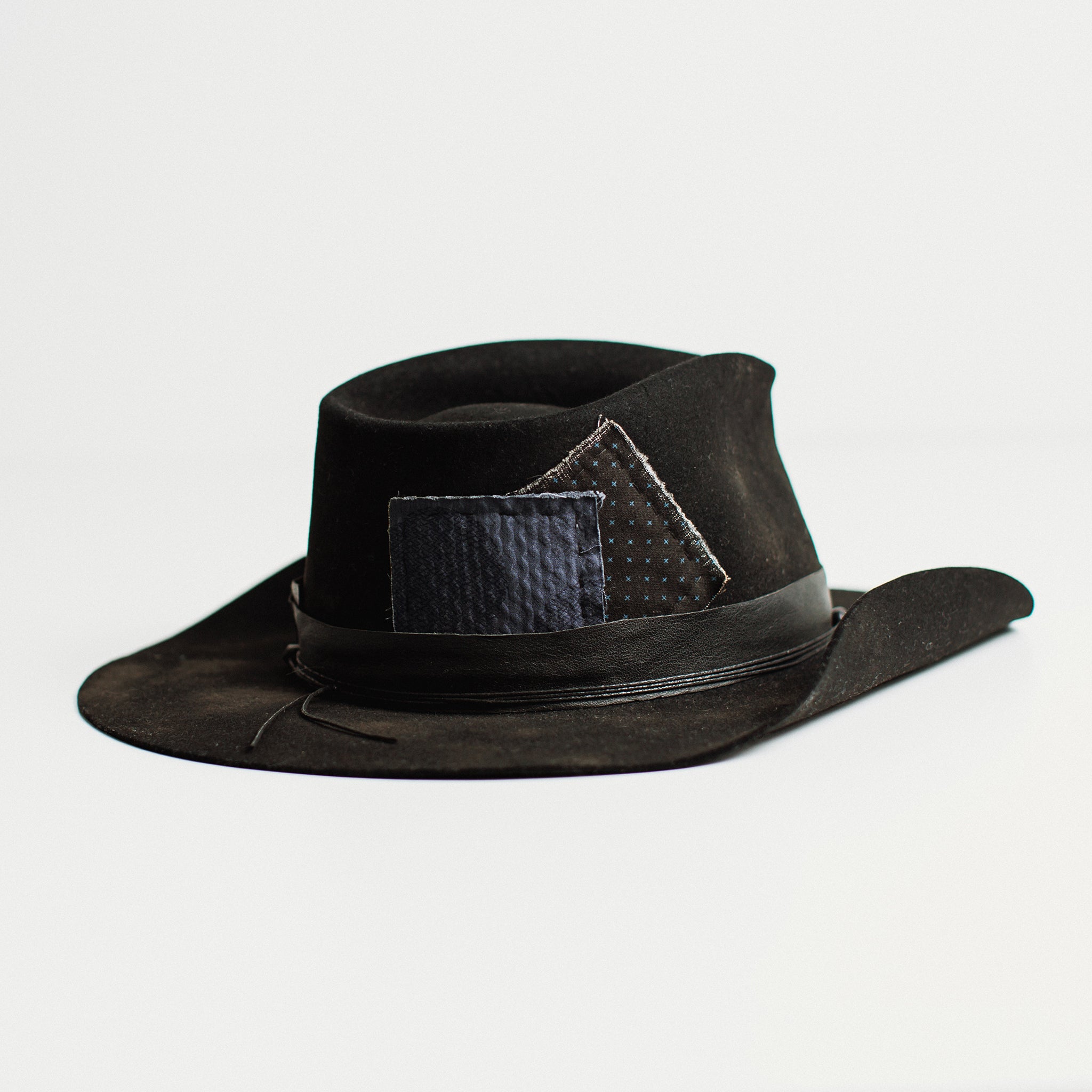 Back angle – The Urban Cowboy by PHYLLi, a handcrafted Black felt hat with suede string, skull beading and visible patches.