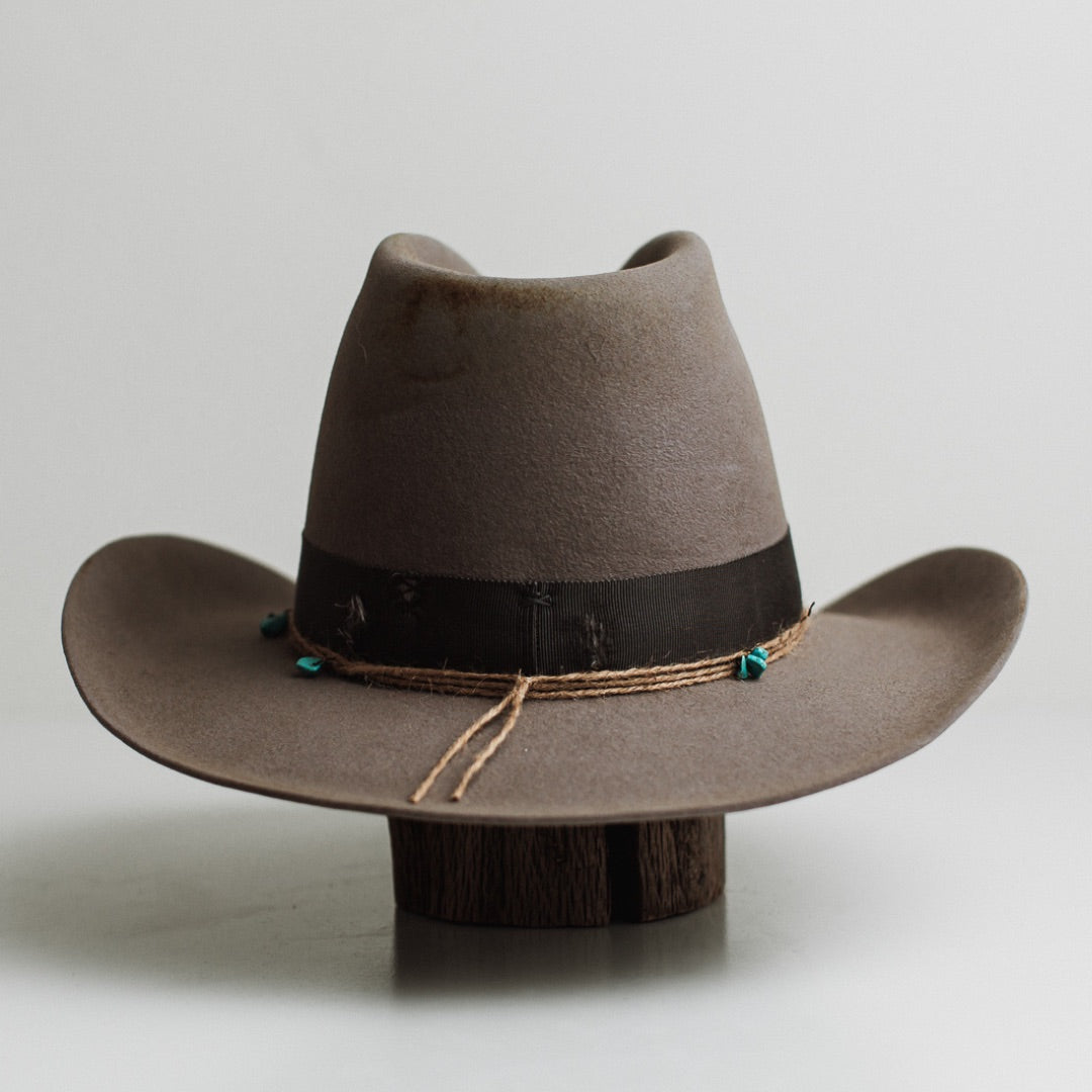Back view of the Finse cement felt cowboy hat by PHYLLi Designs featuring distressed steel grey grosgrain band and twine wrap with turquoise beading.