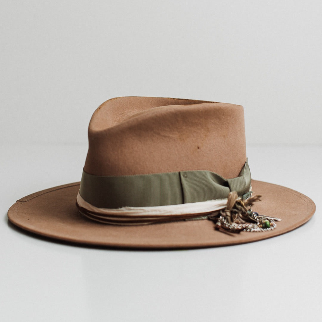 Front left angle of the Nim camel distressed felt hat by PHYLLi Designs with oil green Japanese grosgrain bow band, taupe brim trim and sari silk tie dye trimming.