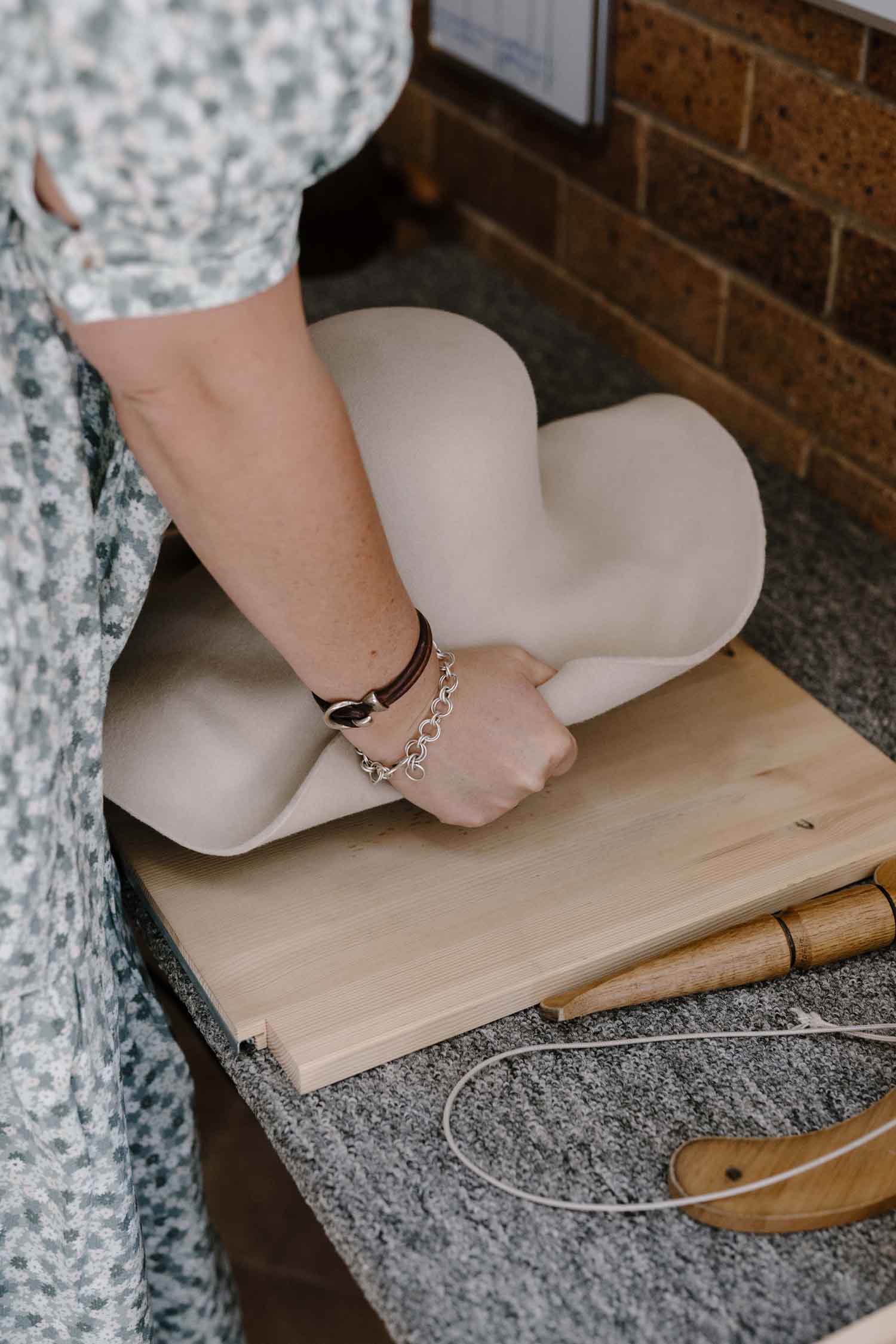 Laura Hall, founder of PHYLLi Designs, blocking a felt hat base over a traditional wooden hat block.
