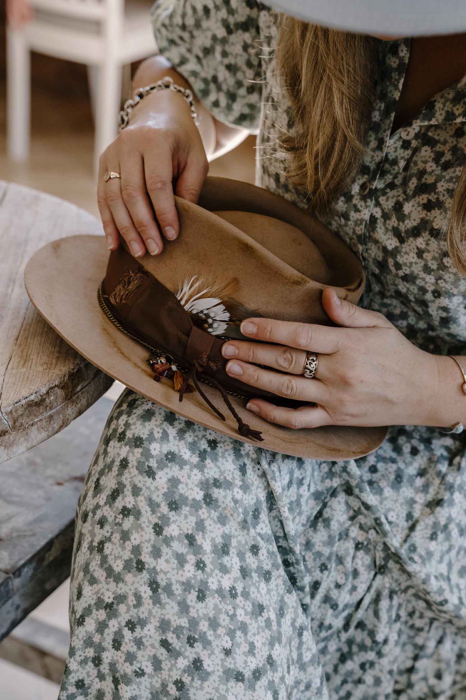 Close-up of Laura Hall adjusting a feather detail on a handcrafted felt hat.