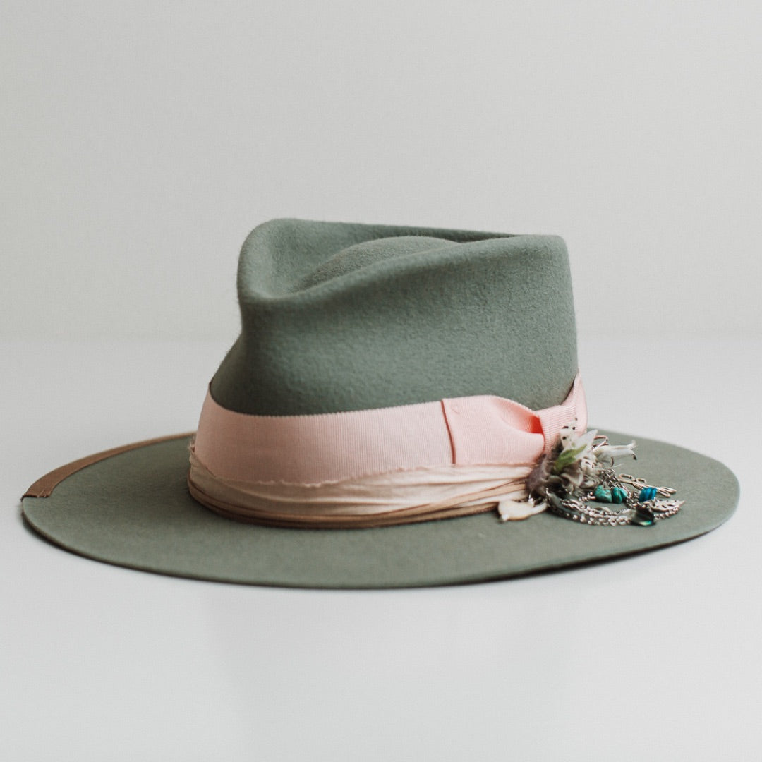 Front left angle of The Sage sage felt hat by PHYLLi Designs with sherbet pink grosgrain bow band and baby pink sari silk trimming.