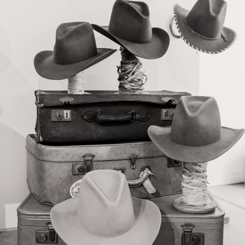 Stack of vintage suitcases topped with custom felt hats from the PHYLLi Hat Bar, showcasing Australian hat making and travel-inspired styling