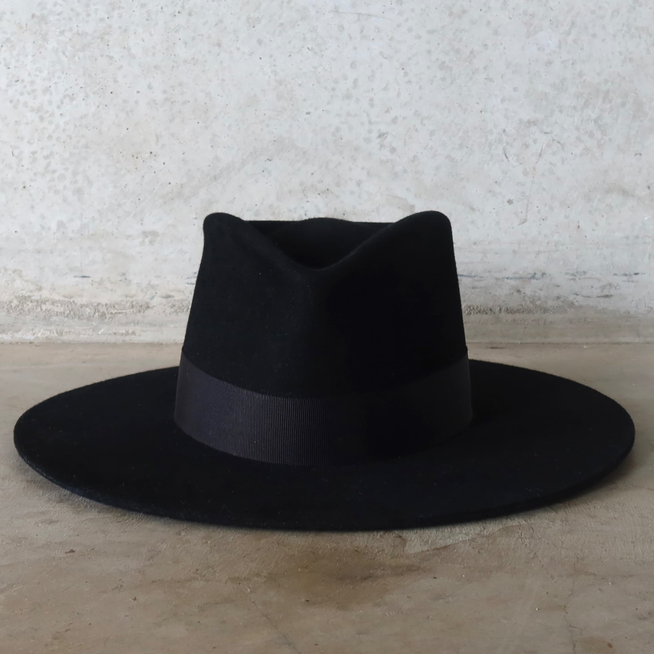 Black felt hat on a textured surface with a neutral background