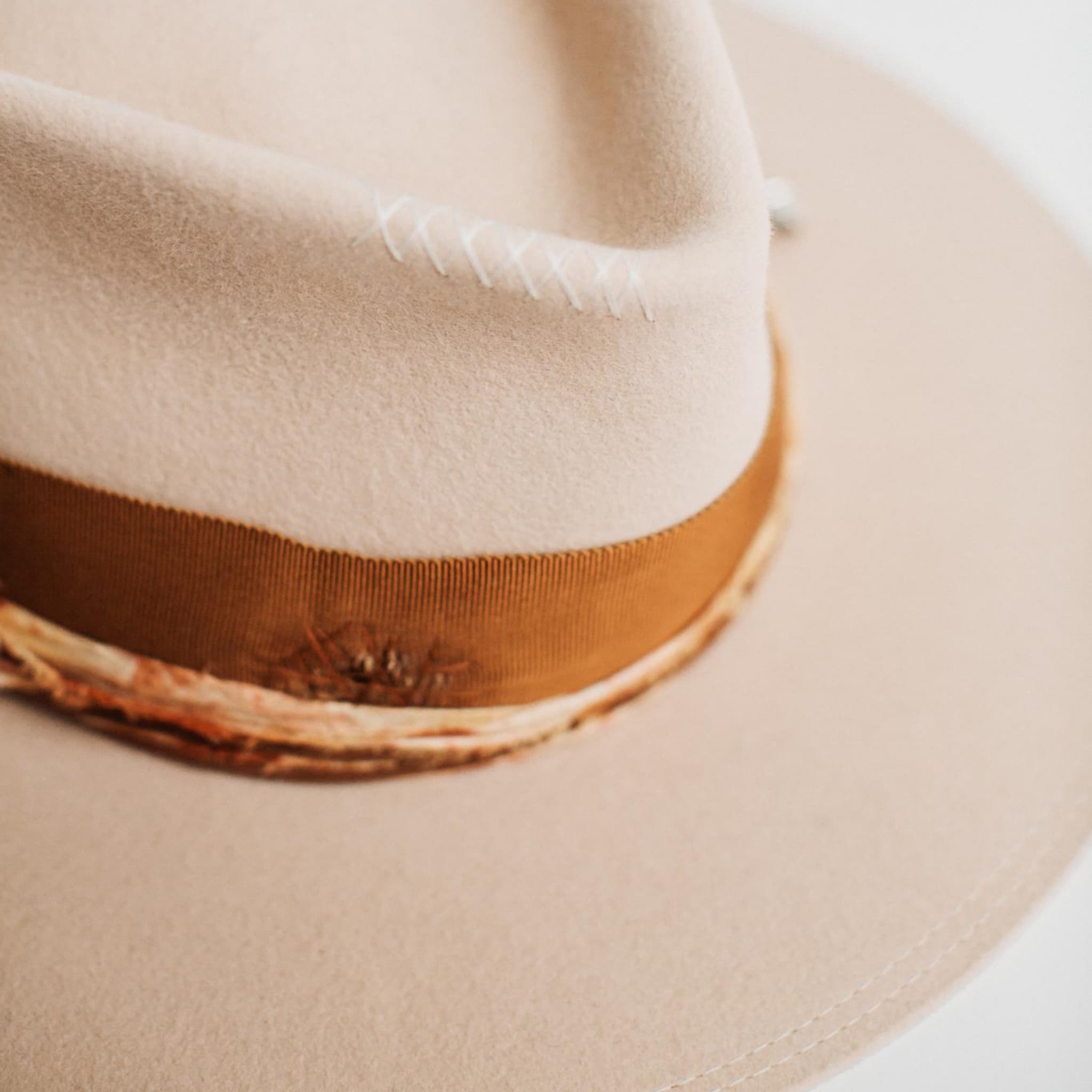 Close-up detail of Malibu beige felt hat by PHYLLi Designs showing copper band, sari silk trim and cross stitching.
