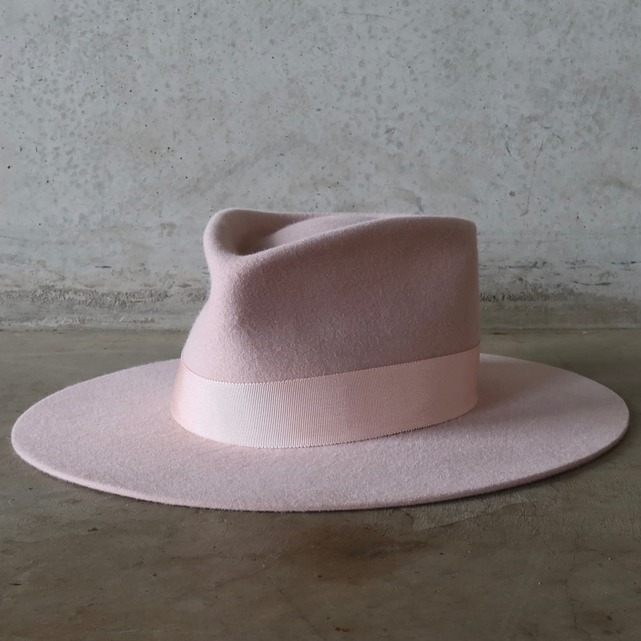 Pink felt hat with a wide brim on a textured surface