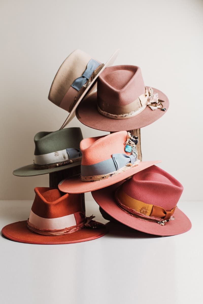 Stack of colorful felt hats with decorative elements on a light background