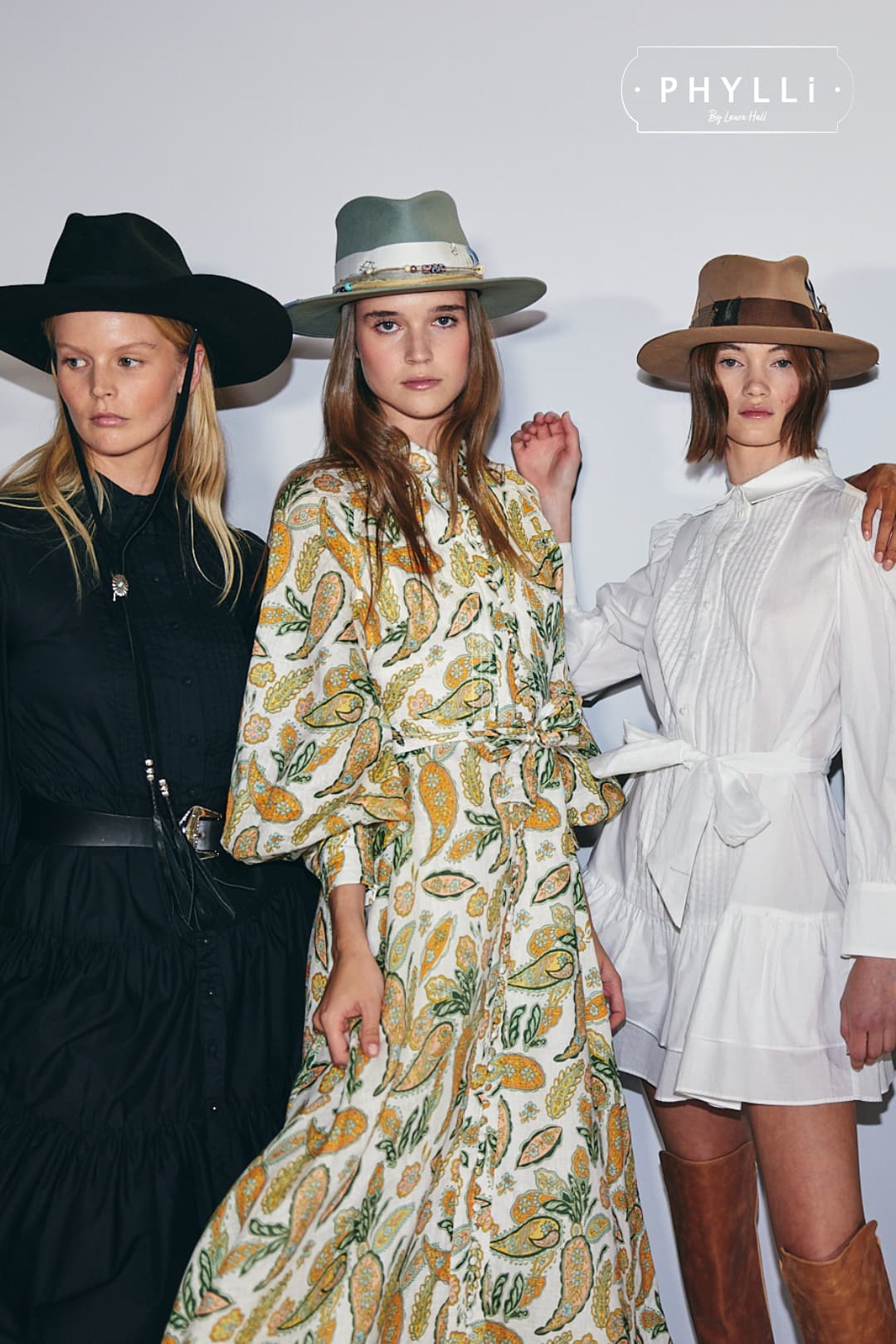 Woman wearing the Accra sage felt hat by PHYLLi Designs with ivory grosgrain band and glass bead detailing in backstage fashion presentation setting.