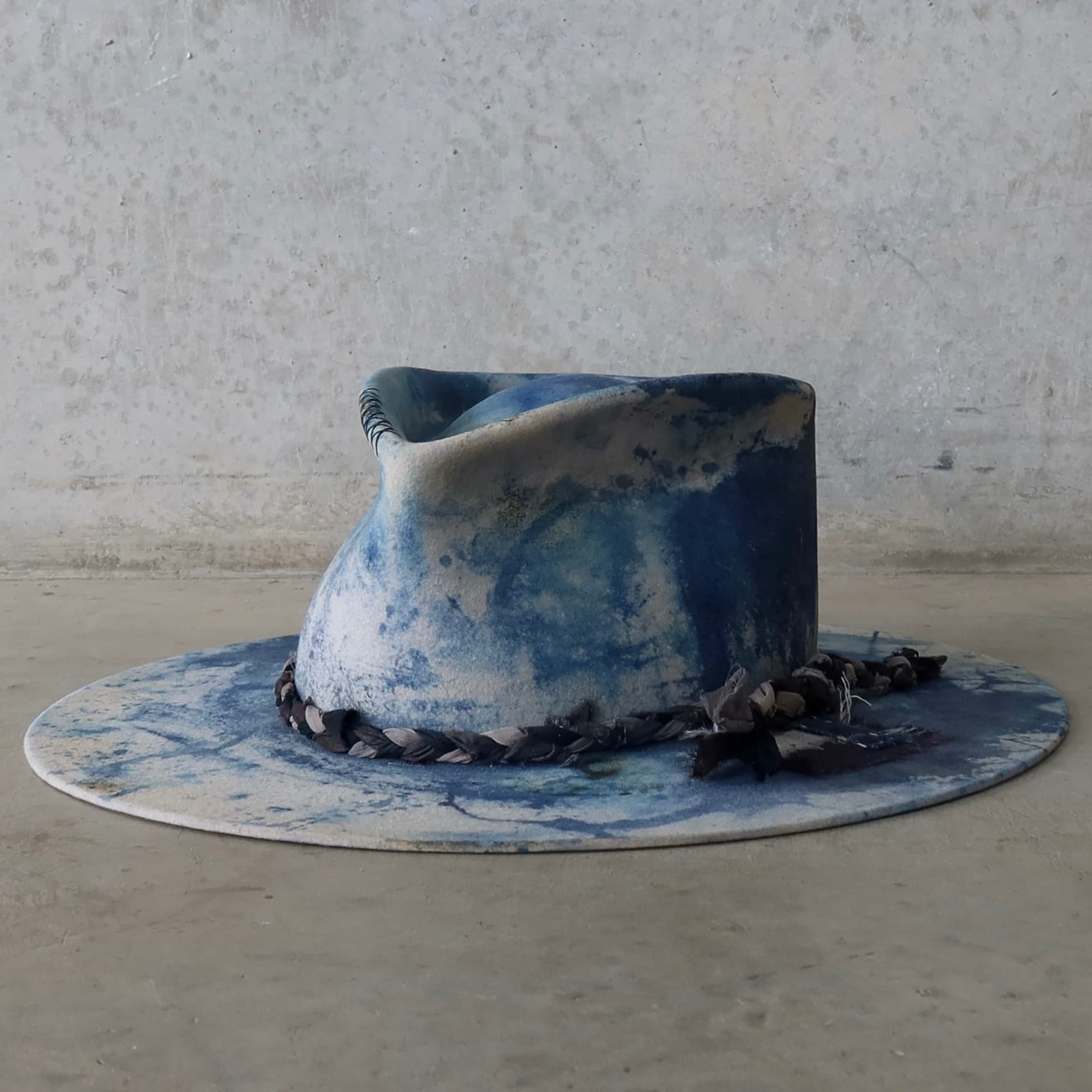 Front left angle of the dove grey indigo tie dye felt hat Aizome Limited Edition by PHYLLi Designs with plaited sari silk trimming.