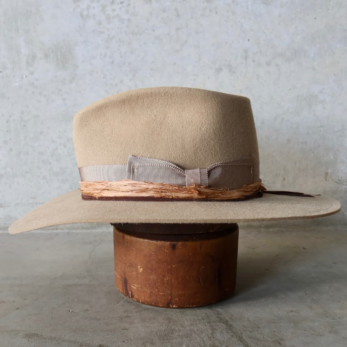 Left side view of the Alexander Camel felt hat by PHYLLi Designs with chocolate suede string and wooden bead detailing.