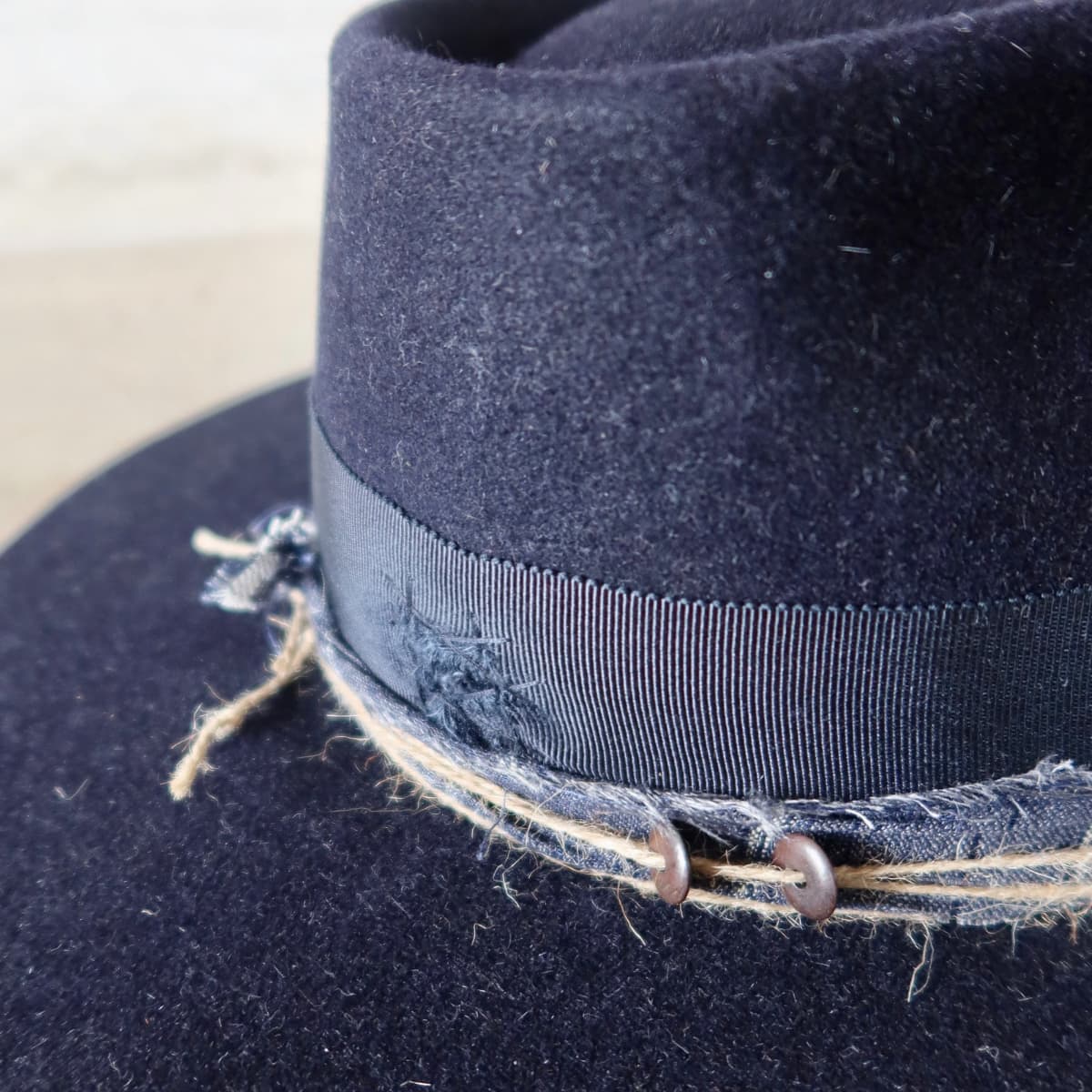 Close up detail of the Armadale felt hat showing pinstripe cotton trim with three twine wraps and assorted bone bead detailing.
