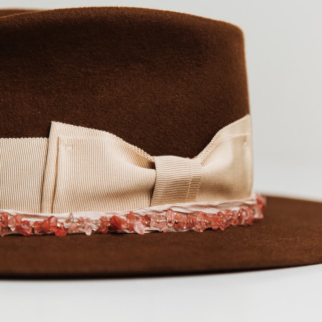 Close up detail of the Australis felt hat showing rose quartz crystal hat necklace along the brim.