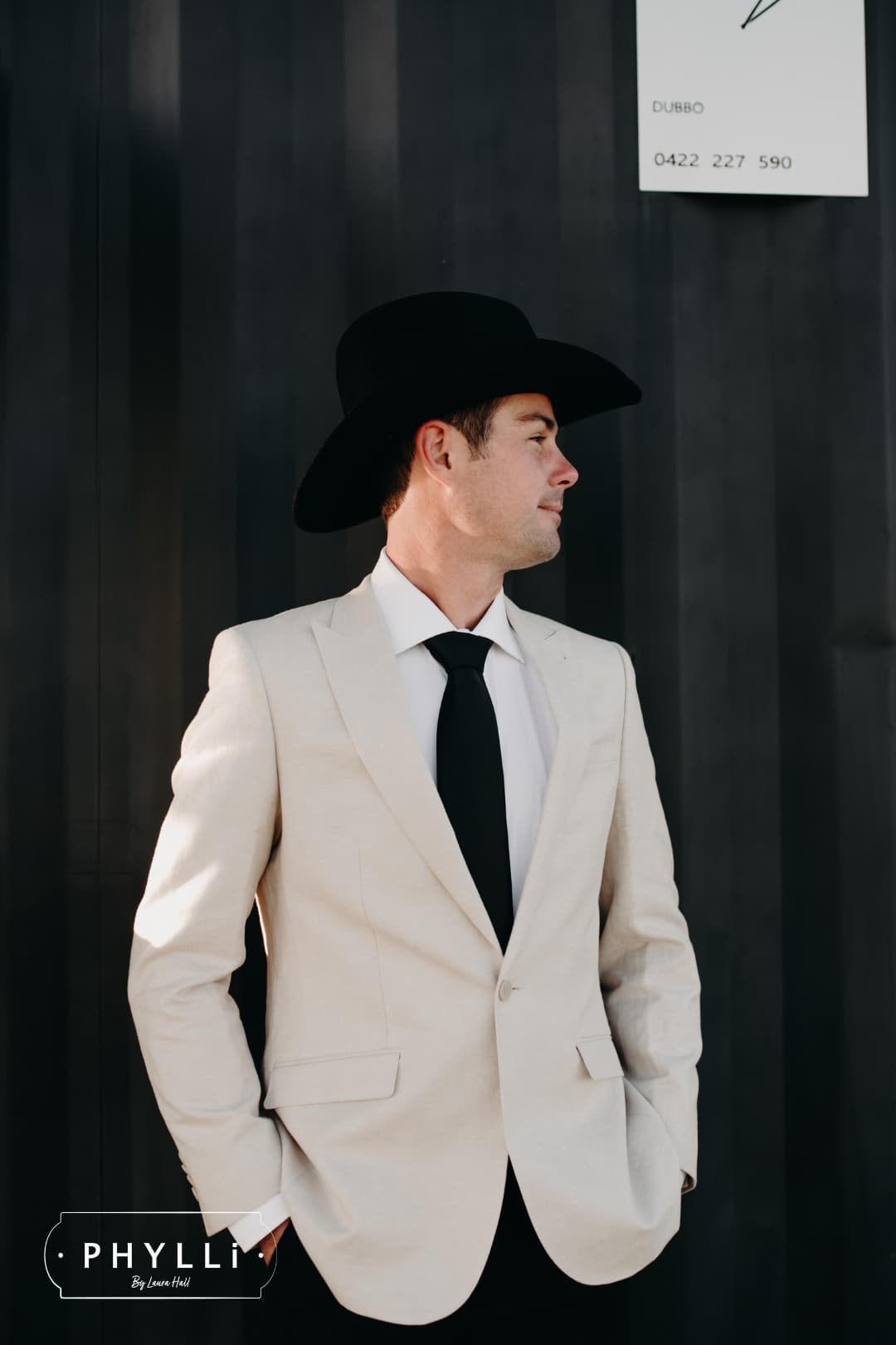 Male model wearing the black felt cowboy hat B&W Wheeler by PHYLLi Designs with black Japanese grosgrain band in a modern bar exterior setting.