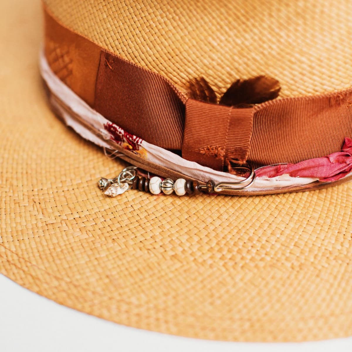 Close up of the Barbados Panama hat trim featuring sari silk, copper band and charm hat pin.