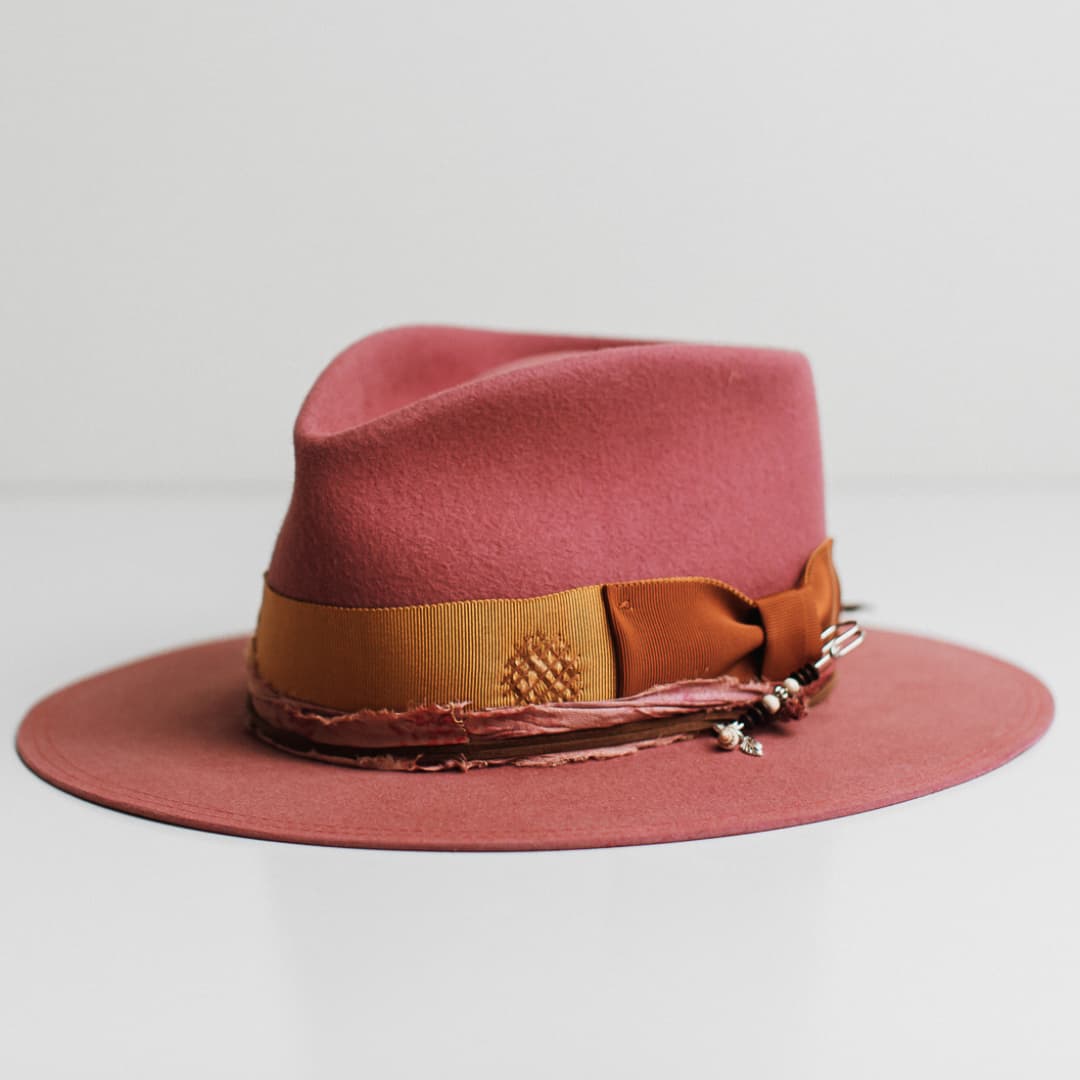 Front left angle of the Barbados Rose rose felt hat by PHYLLi Designs with distressed turmeric grosgrain band, rust bow and sari silk trimming.