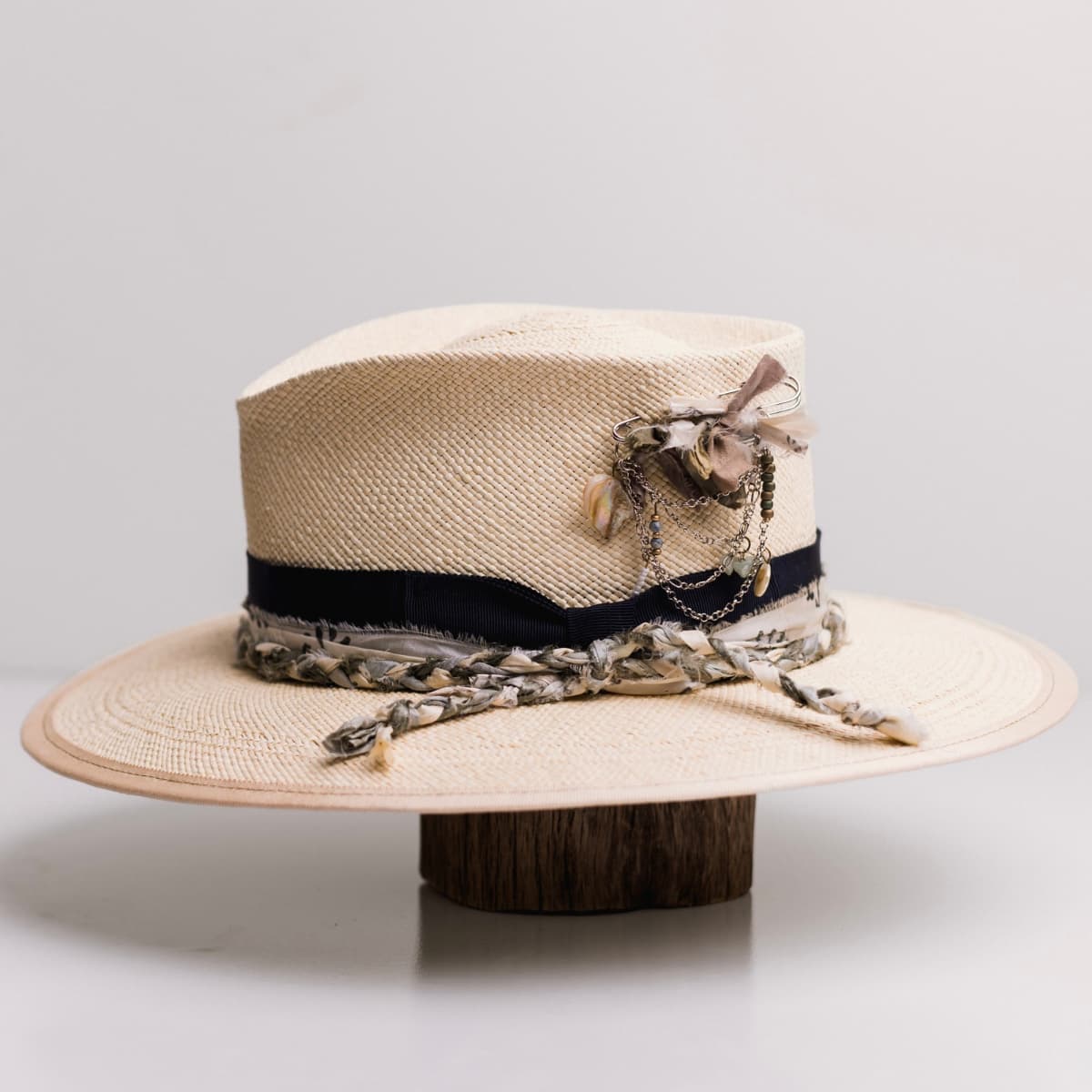 Left side view of the Blue Jean Natural Panama hat by PHYLLi Designs with silver chunky hat pin featuring sari silks, charms and pearl.