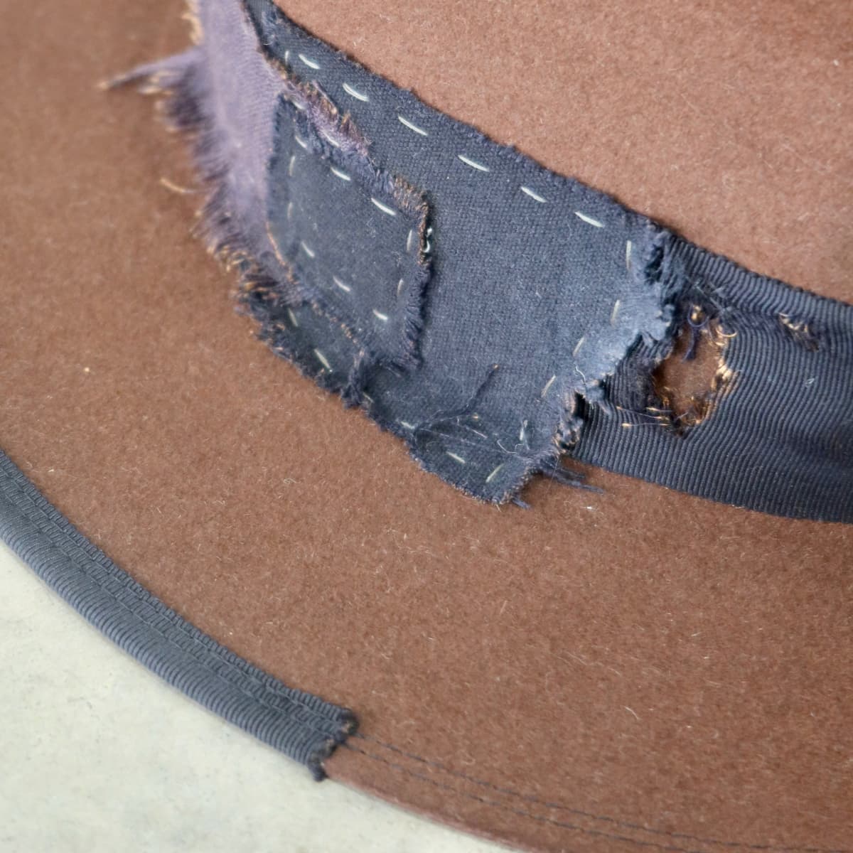 Close up detail of the Brenner Limited Edition felt hat showing distressed denim and linen patchwork stitching.