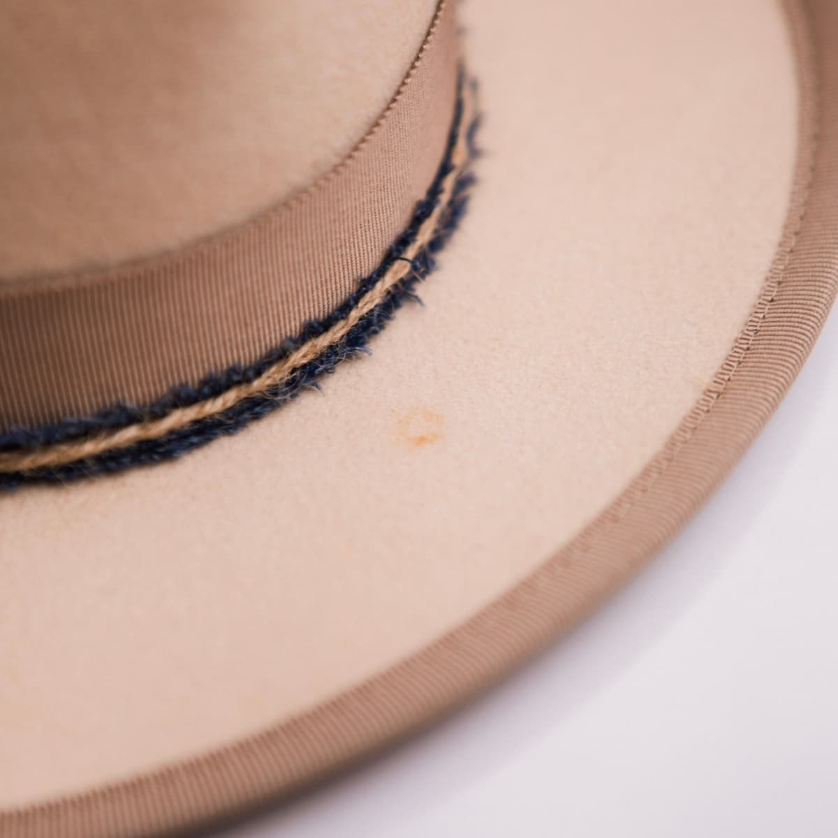 Close up detail of the Buckler felt hat showing the distressed beige felt crown above the taupe grosgrain band.