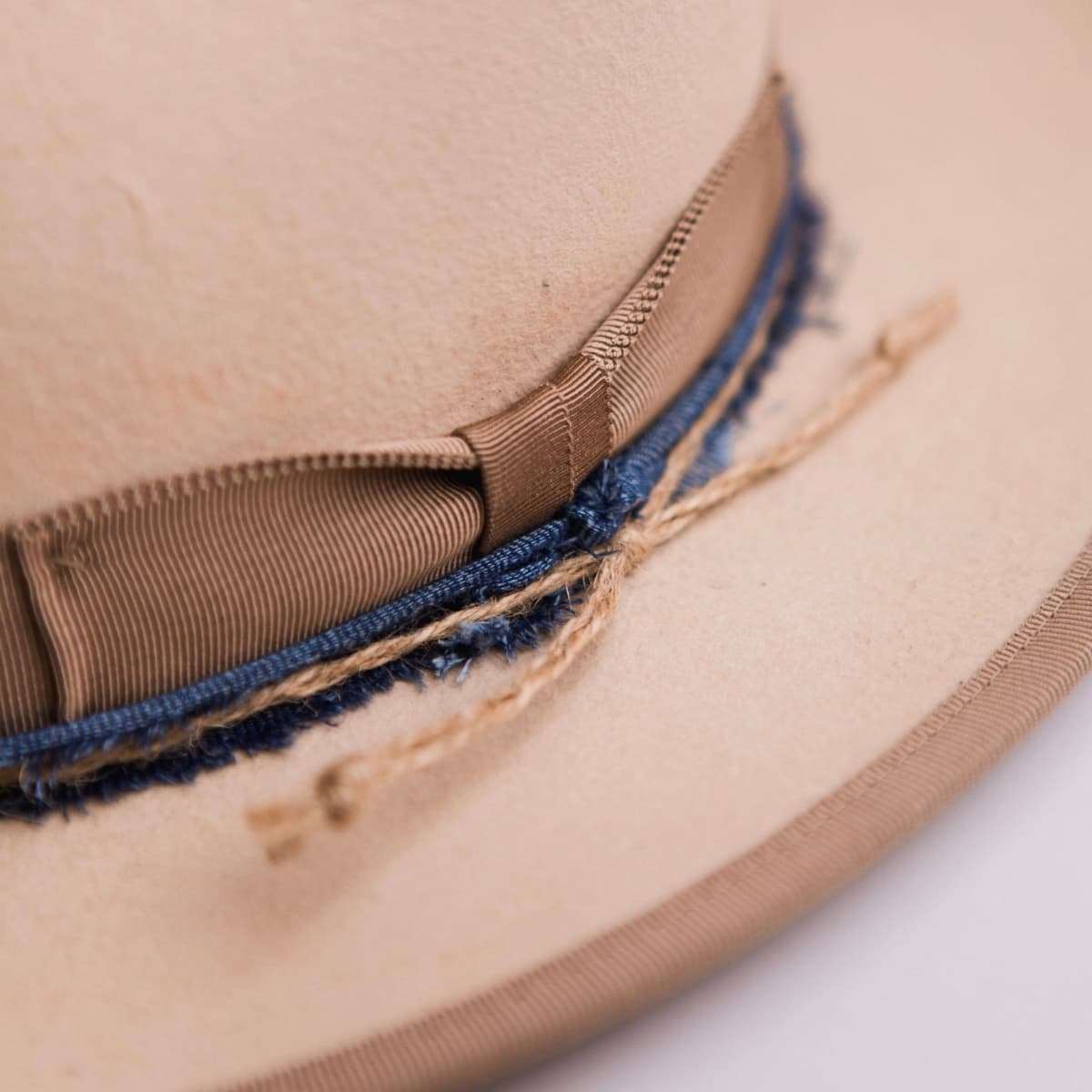 Close up detail of the Buckler felt hat showing the taupe Japanese grosgrain bow band with denim trimming and twine plait.