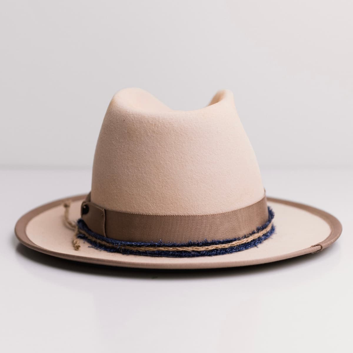 Back view of the Buckler beige felt hat by PHYLLi Designs featuring denim trimming finished with a twine plait.