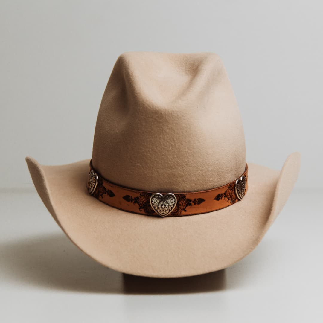 Phylli x Buffalo Girl Palamino Heart Concho Hat Band with hand tooled Palamino leather Mandala hat band featuring three silver heart conchos on a beige felt cowboy hat by PHYLLi Designs.