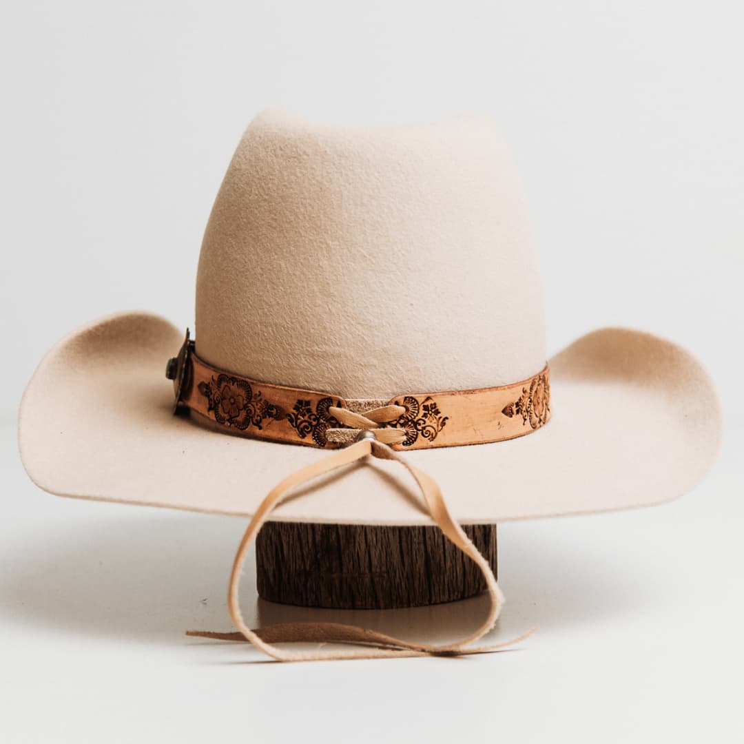 Back view of the PHYLLi x Buffalo Girl Palamino Mandala Hat Band with Navajo Concho featuring smoke deer hide lace tie back detail on a beige felt cowboy hat by PHYLLi Designs.