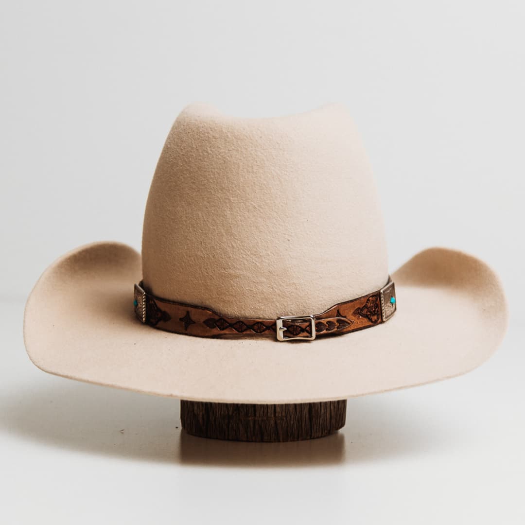 Back view of the PHYLLi x Buffalo Girl Rugged Desert Buckle Hat Band featuring antique brown leather hat band fastened with western style buckle on a beige felt hat by PHYLLi Designs.