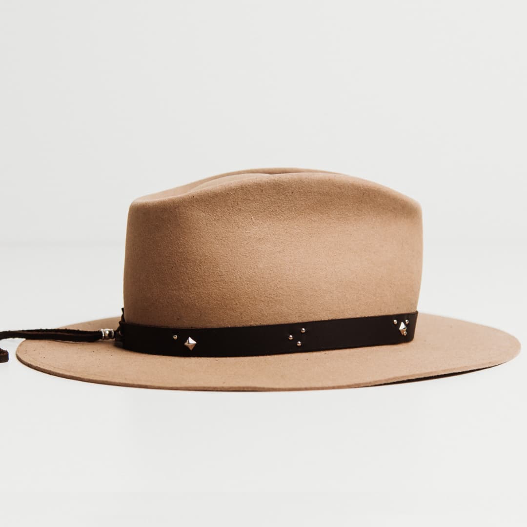 Right side view of the Buffalo Tieback Studded Hat Band featuring dark brown buffalo hide band with stainless steel studded detailing on a Sahara felt hat by PHYLLi Designs.