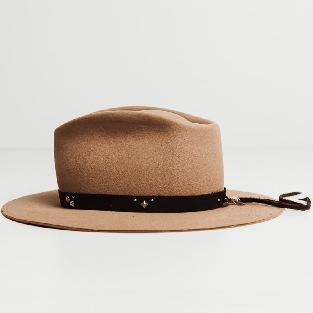 Left side view of the Buffalo Tieback Studded Hat Band featuring dark brown buffalo hide band with stainless steel studded detailing on a Sahara felt hat by PHYLLi Designs.