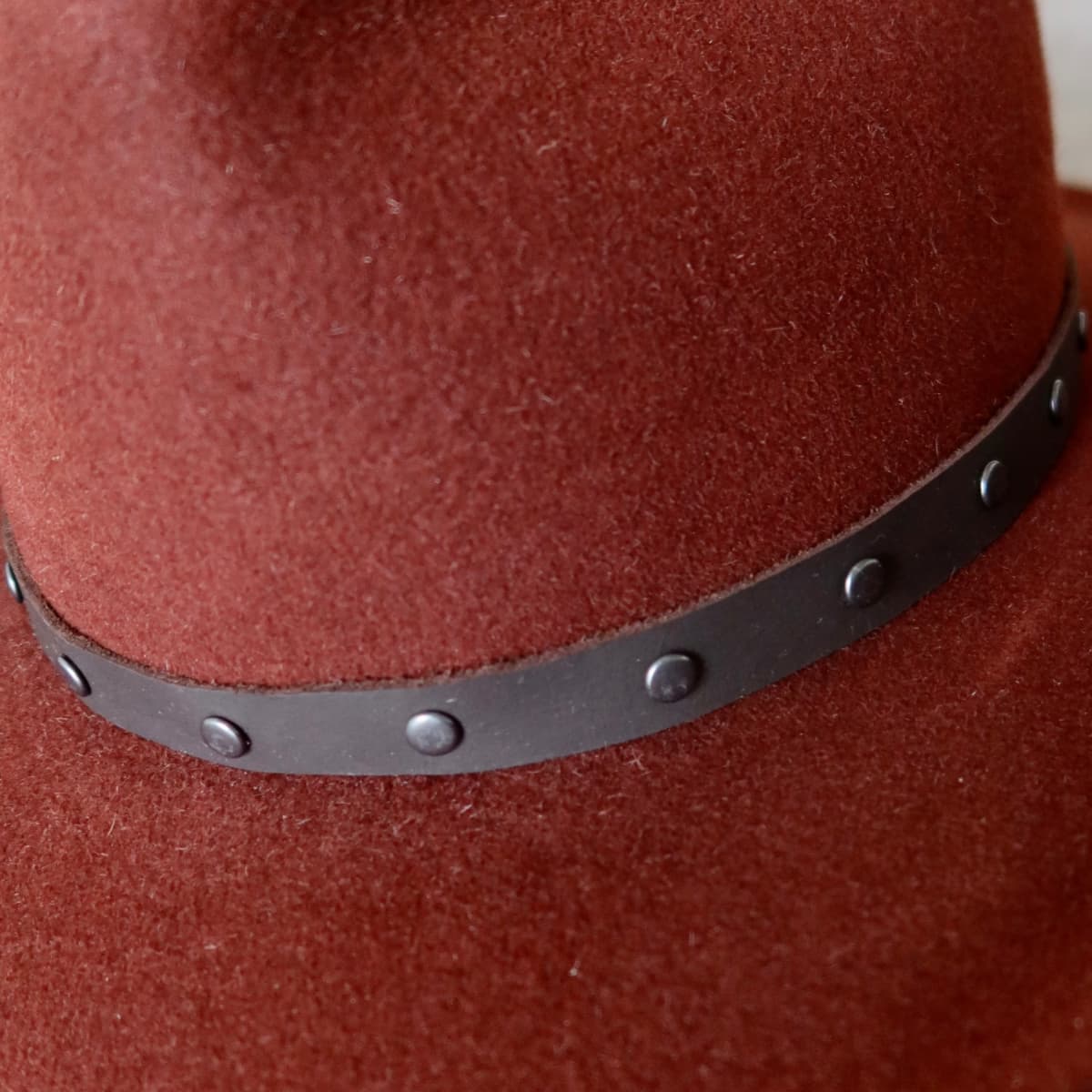 Close up detail of the Burgundy felt cowboy hat showing gunmetal studded leather hat band.