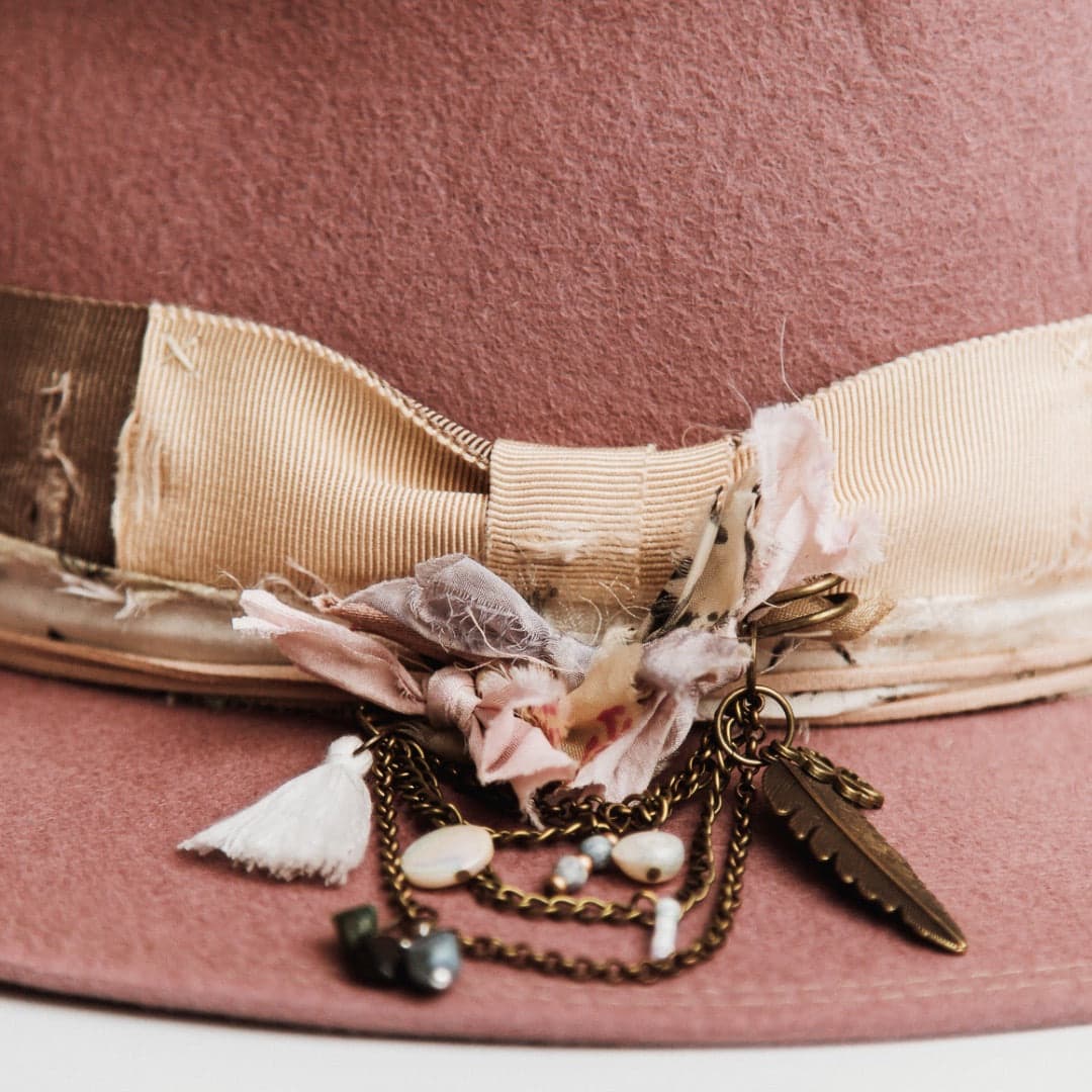 Close up detail of the Celia felt hat showing bronze chunky hat pin with sari silks, tassel, charms and beads.