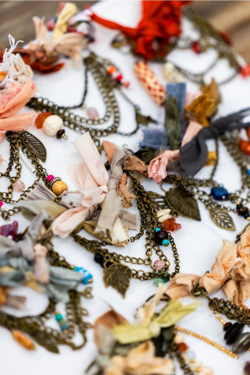 Close up detail of chunky hat pins showing neutral sari silk ribbons with antique bronze chains, gemstone beads and leaf charms.