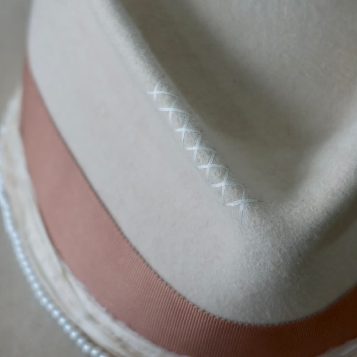 Close up detail of the Clementine felt hat showing ivory hand-stitched cross detail.