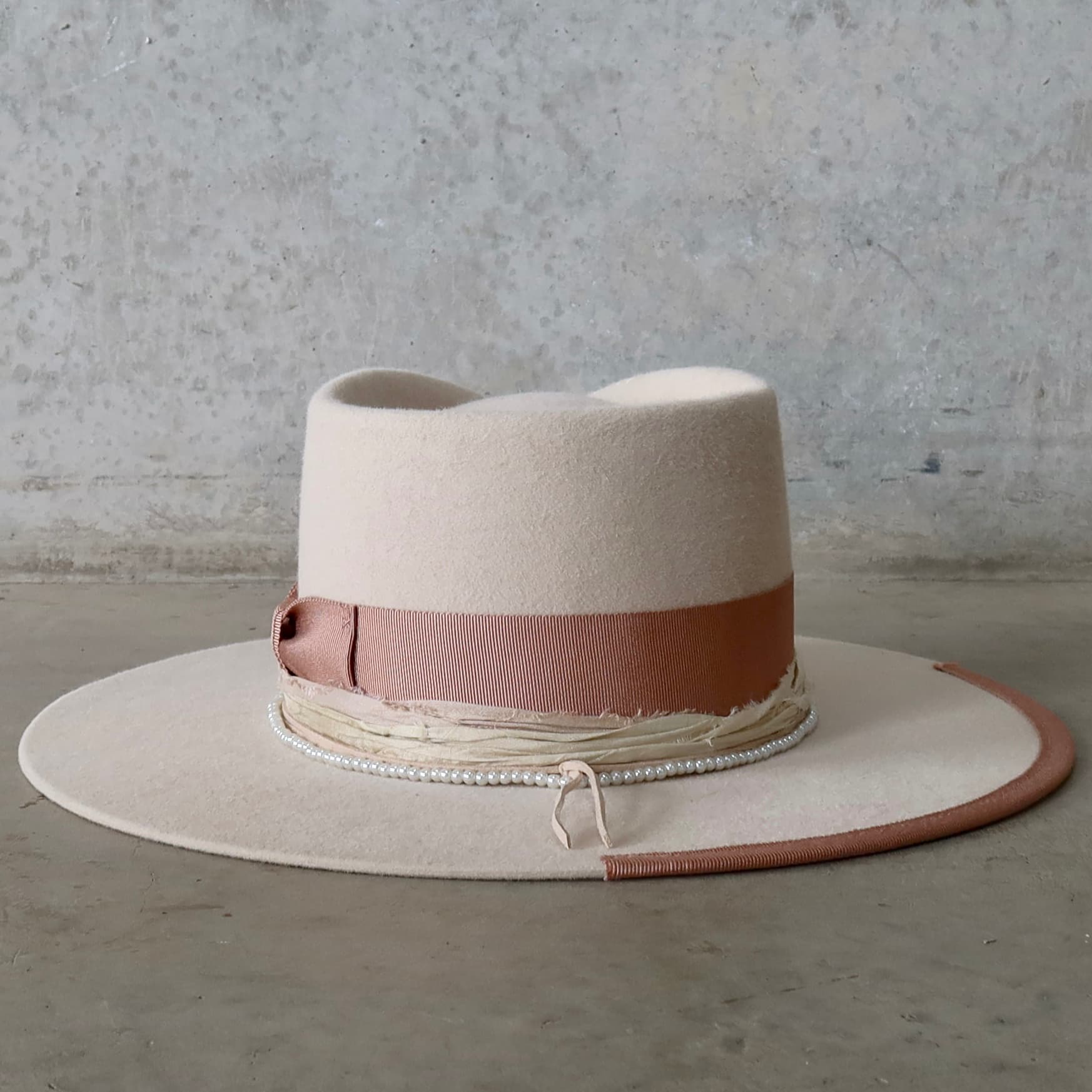 Back view of the beige felt hat Clementine by PHYLLi Designs featuring pearl hat necklace and nude suede tie.
